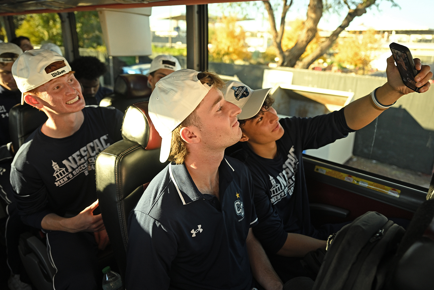 Three soccer players on a bus take a selfie photo together.