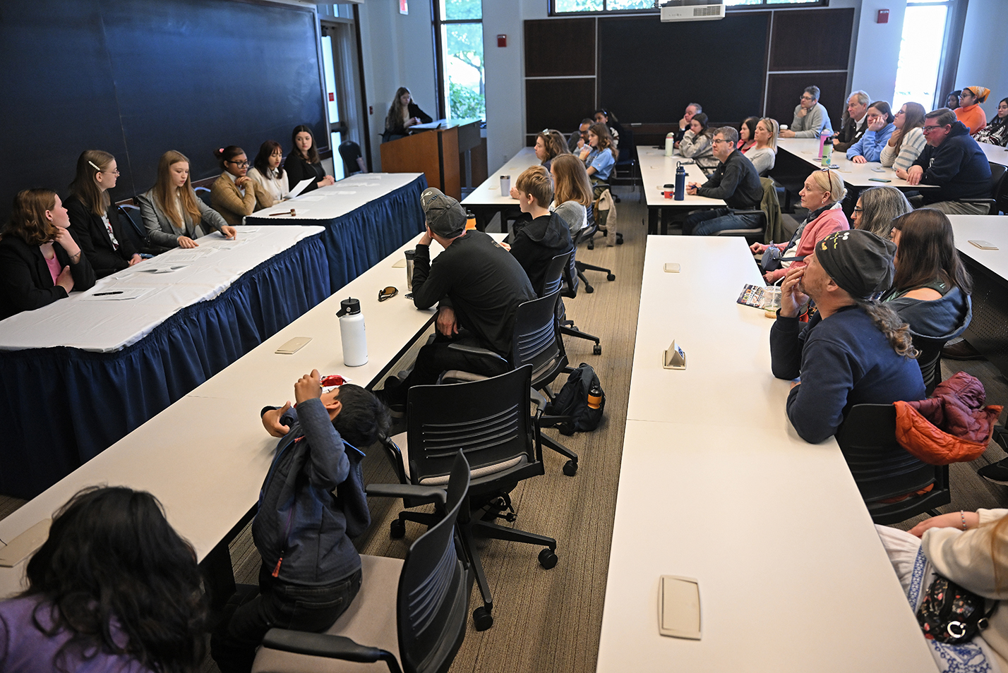 An audience watches as a mock trial club stages a hearing.