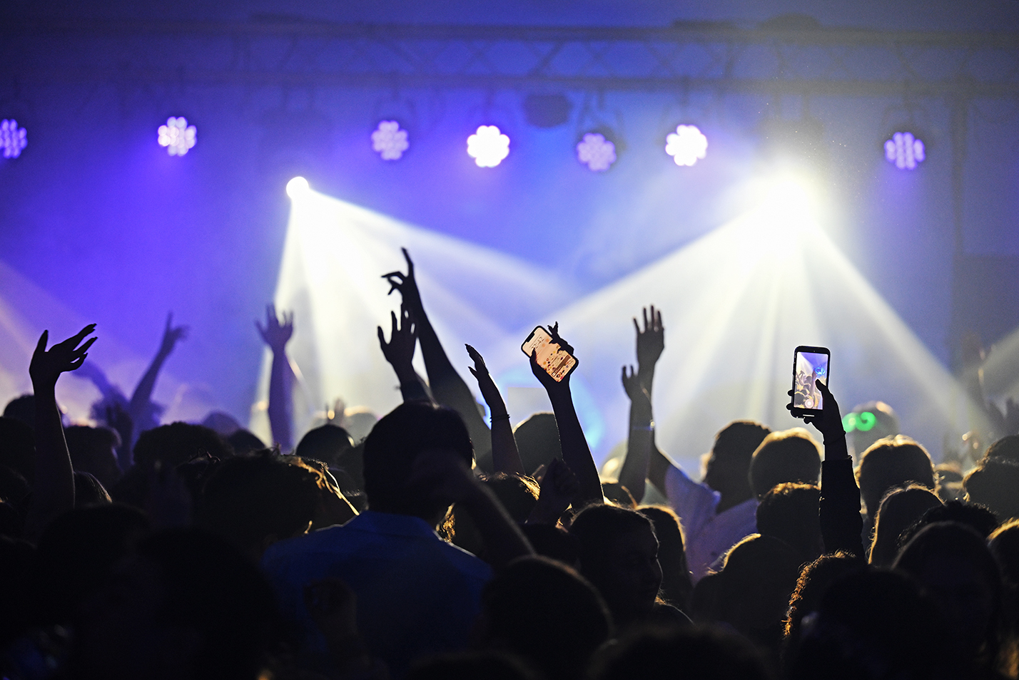 Students dancing to a DJ are seen in silhouette against the stage lights.