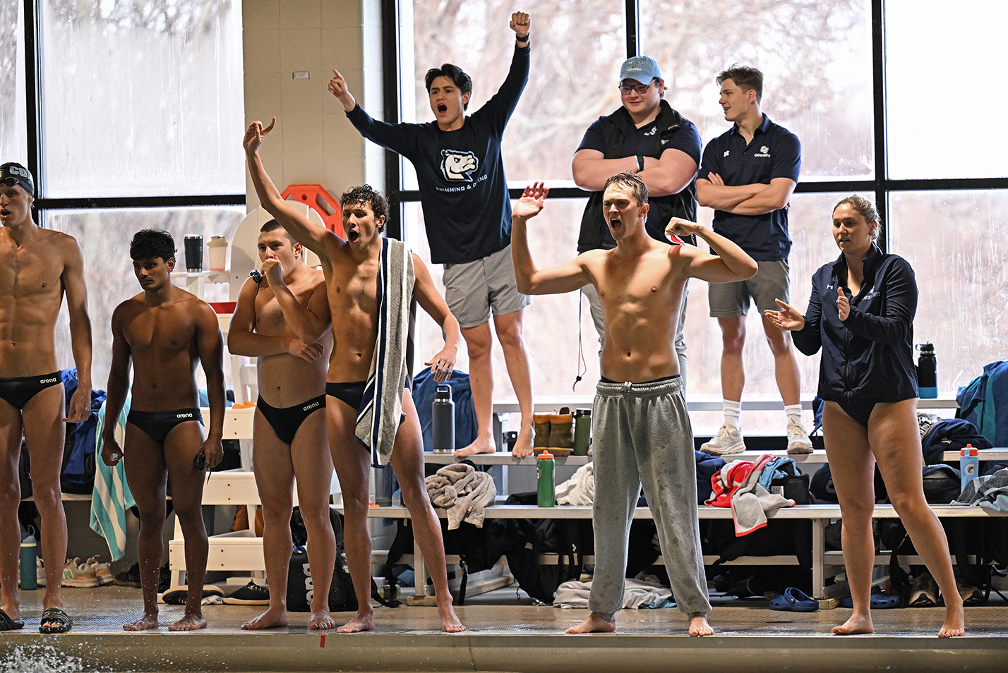 Swim team members cheer from the poolside during a race.